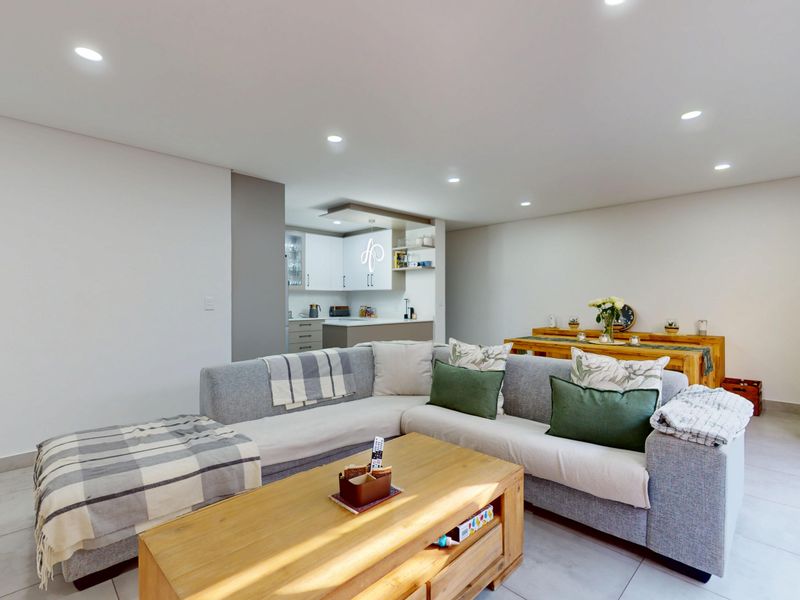 Modern open-plan living area featuring tiled floors, recessed lighting, and a seamless transition to a contemporary kitchen with ample cabinetry.