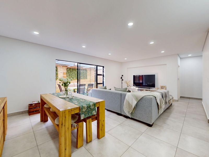 Spacious open-plan living and dining area featuring modern tiled flooring, recessed lighting, and large sliding glass doors leading to the outdoor patio.
