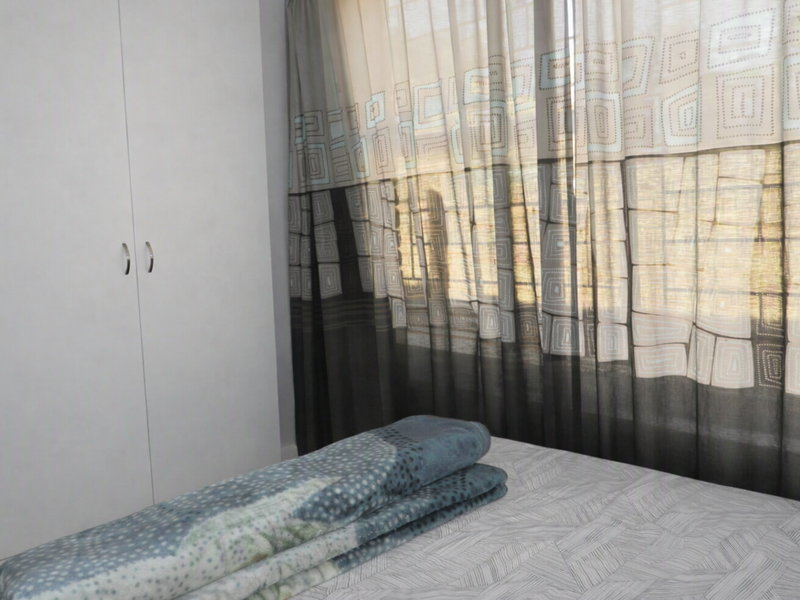 A bedroom featuring a built-in wardrobe and window with patterned curtains.