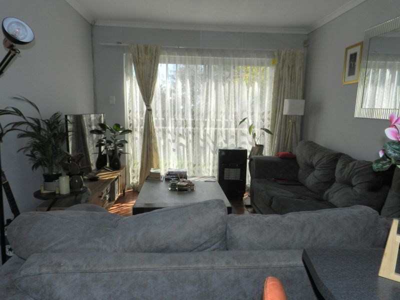 A comfortable living room featuring tiled flooring and a large sliding glass door that provides natural light and access to the outdoor area.