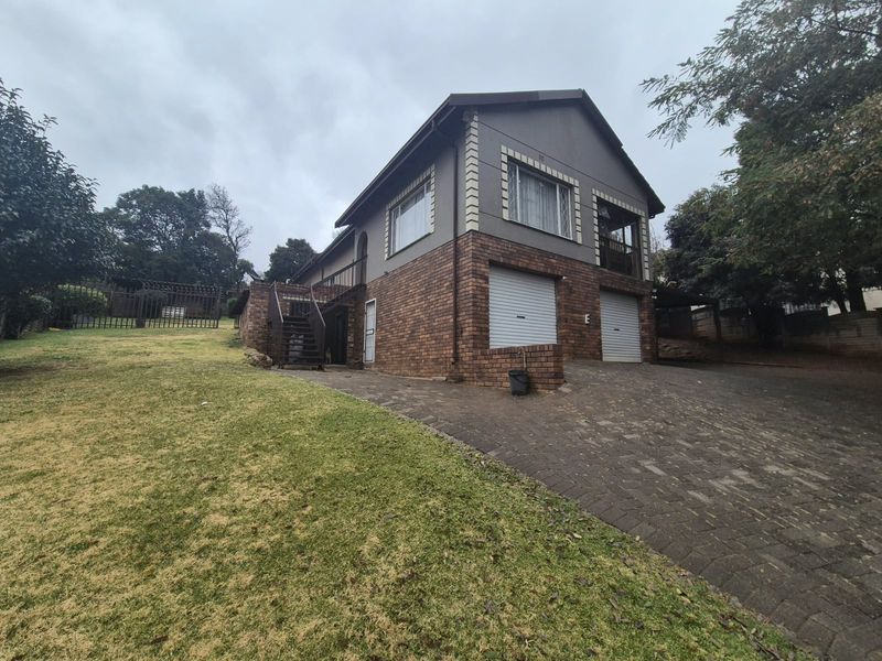 Front view of a two-story brick house featuring a double garage, paved driveway, and an external staircase leading to the upper level.