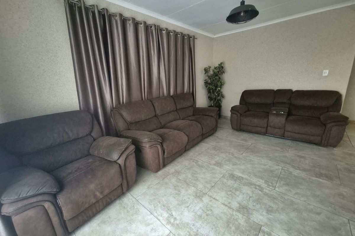 A living room featuring large format floor tiles, neutral wall finishes, and a central pendant light fixture.