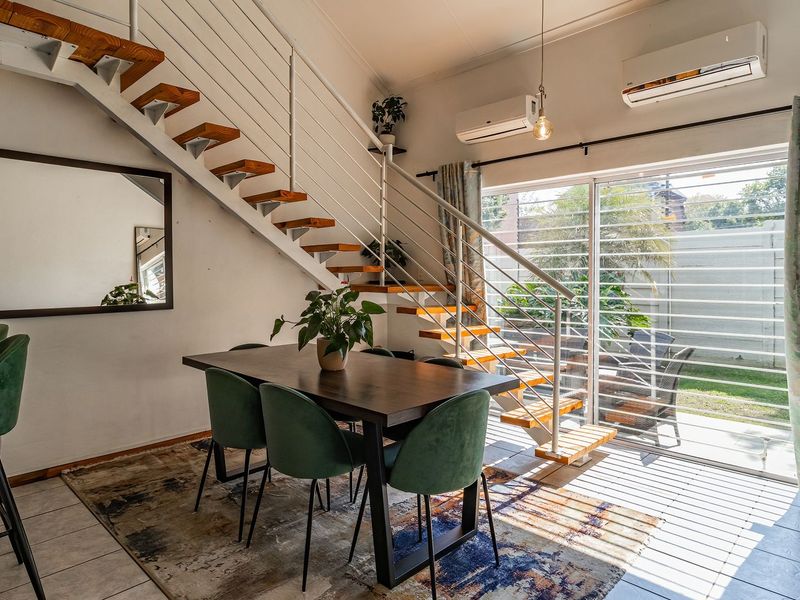 Open-plan living and dining area featuring a modern staircase, tiled floors, and large sliding doors providing access to the rear garden.