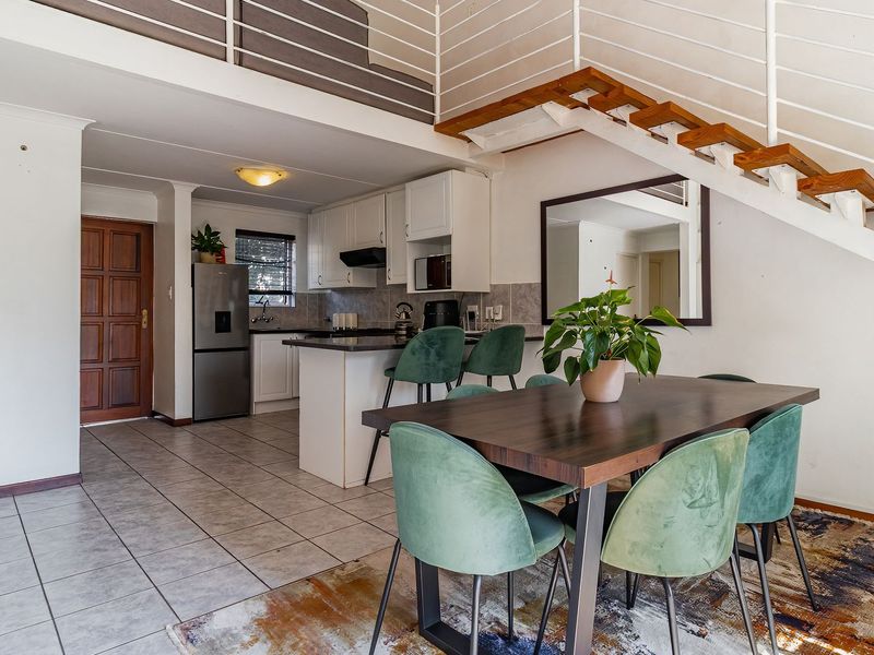 Open-plan living and kitchen area featuring tiled floors, a breakfast bar, and a staircase leading to a mezzanine level.