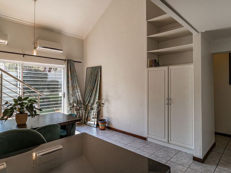 Open-plan living area featuring vaulted ceilings, tiled flooring, built-in storage cabinetry, and a staircase with metal railings.