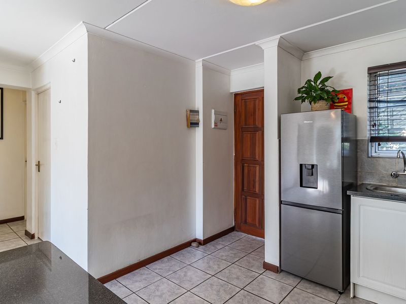 A functional kitchen area featuring tiled flooring, stone countertops, built-in cabinetry, and a stainless steel sink with a mixer tap.
