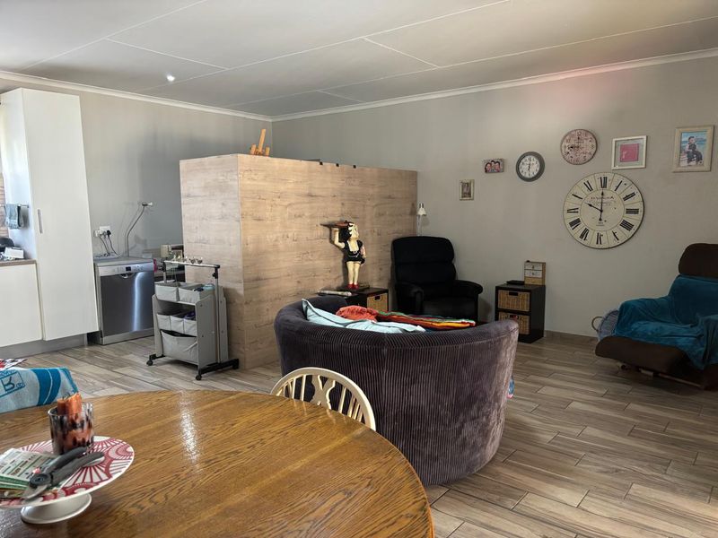 Open-plan living area featuring wood-look tile flooring, a central partition wall, and integrated kitchen cabinetry with a built-in dishwasher.