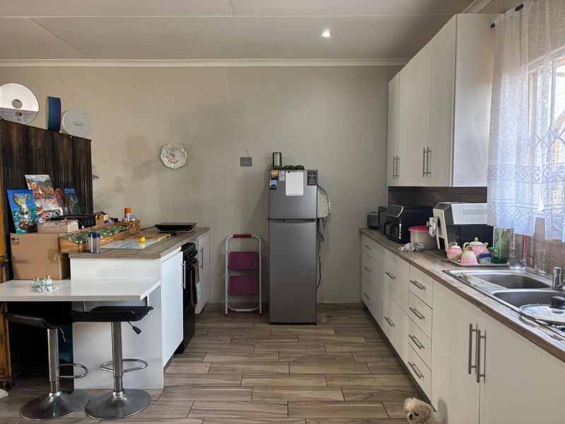 A functional kitchen featuring white cabinetry, wood-look laminate countertops, stainless steel sink, and tiled flooring with recessed lighting.