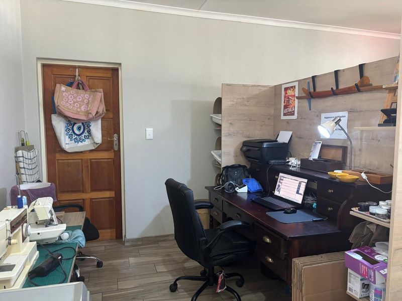 A functional home office space featuring tiled flooring and a solid timber door, currently utilized as a workspace.