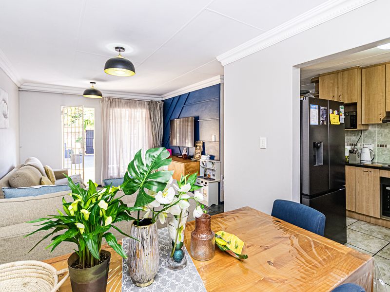 Open-plan living and dining area featuring a functional kitchen with built-in cabinetry, oven, and hob, leading to a bright lounge space.