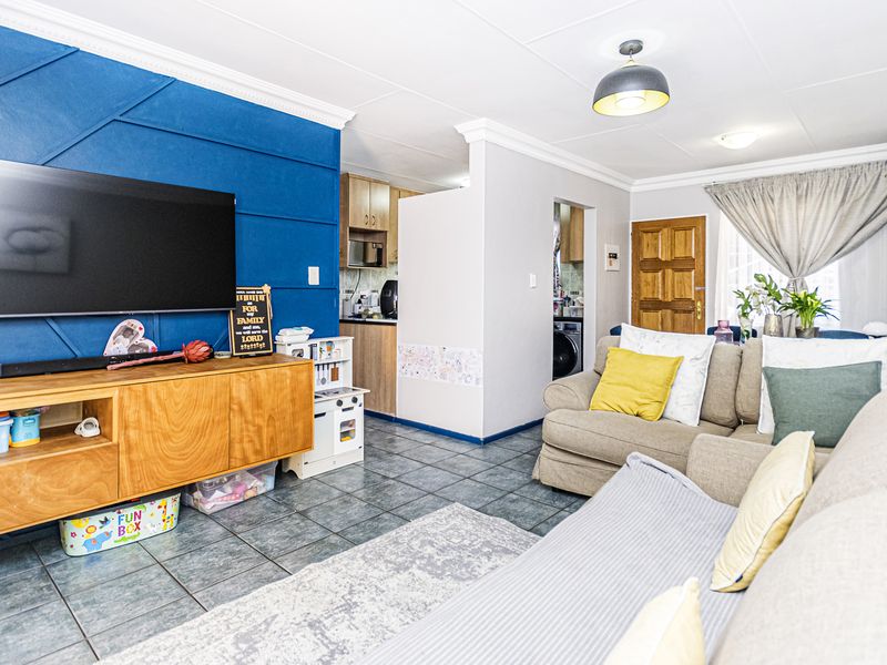 Open-plan living area featuring tiled floors, decorative ceiling cornices, and a direct view into the adjacent kitchen space.