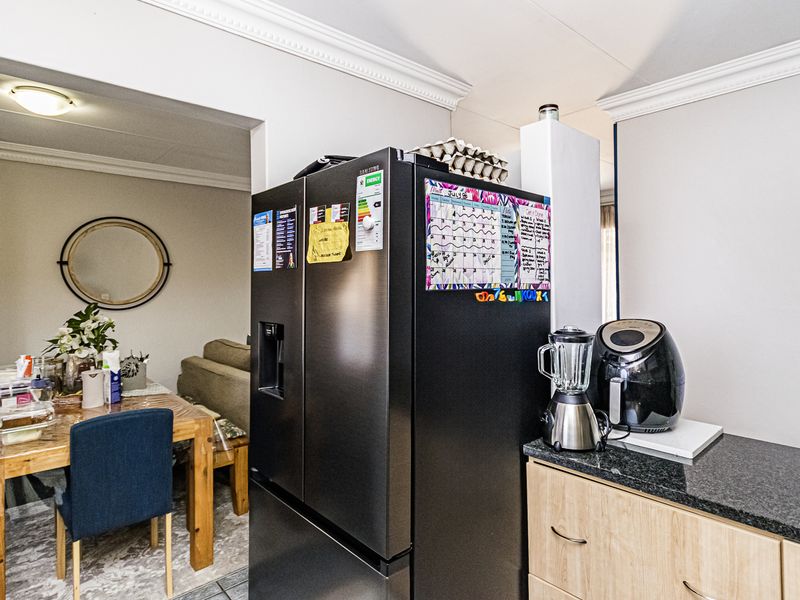 A functional kitchen area featuring granite countertops and laminate cabinetry, with an open-plan layout connecting to the adjacent dining space.