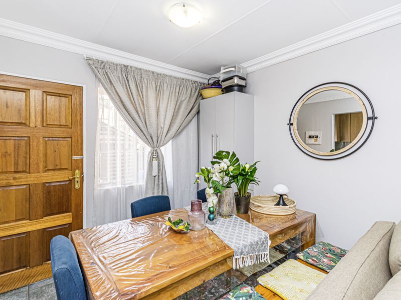A functional dining area featuring tiled flooring, a solid wood entrance door, and decorative ceiling cornicing, providing a practical space for meals.