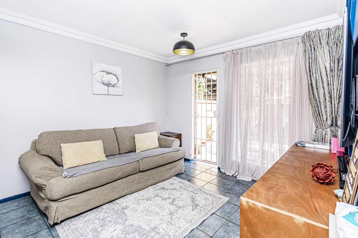A living room featuring tiled flooring, a security gate, and a sliding door providing access to the exterior.
