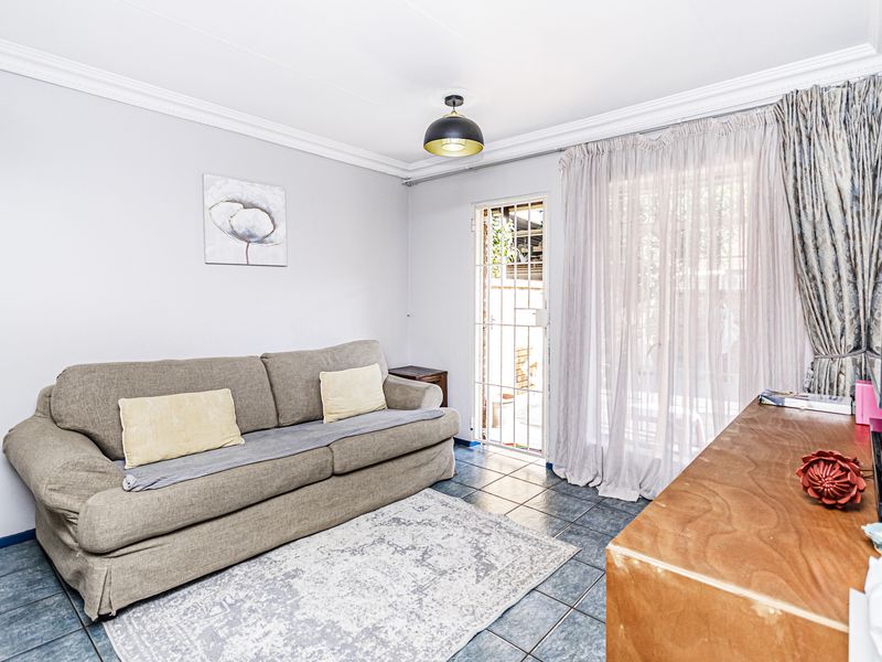 A living room featuring tiled flooring, a security gate, and a sliding door providing access to the exterior.