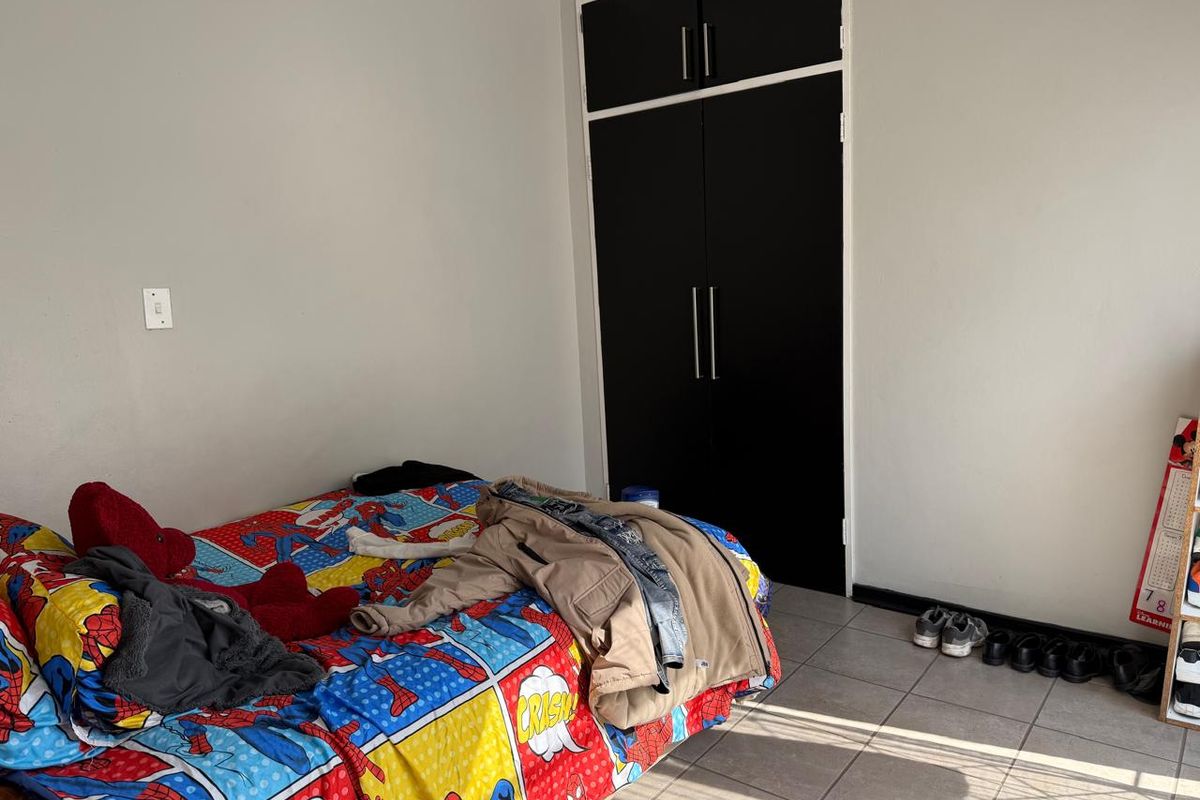 A bedroom featuring tiled flooring and a built-in wardrobe with dark doors.