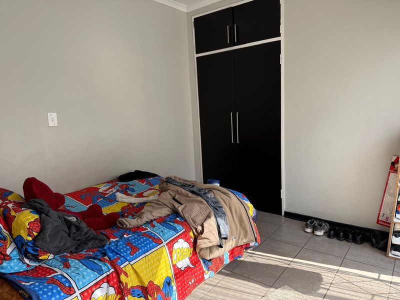 A bedroom featuring tiled flooring and a built-in wardrobe with dark doors.