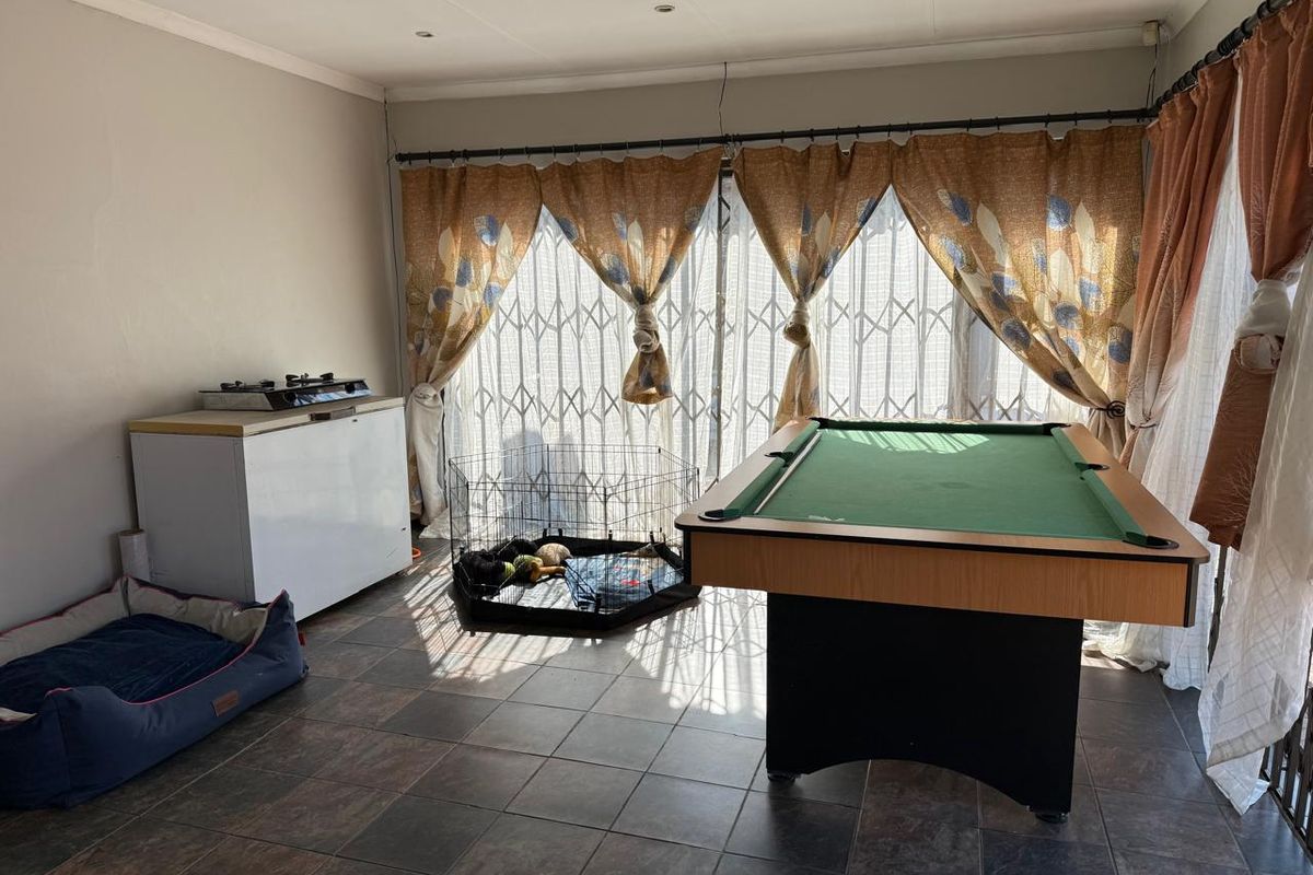 A living area featuring tiled flooring, recessed lighting, and large sliding glass doors with security gates, providing access to the exterior.