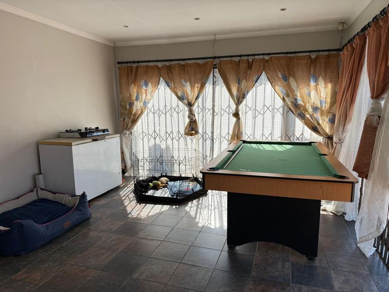 A living area featuring tiled flooring, recessed lighting, and large sliding glass doors with security gates, providing access to the exterior.