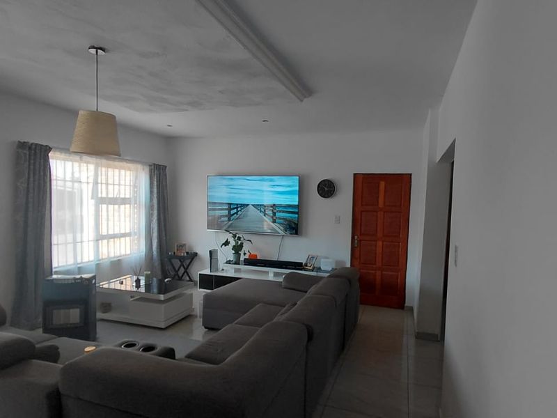 A comfortable living room featuring tiled flooring, recessed ceiling lighting, and a solid timber door, providing a functional and well-maintained space.