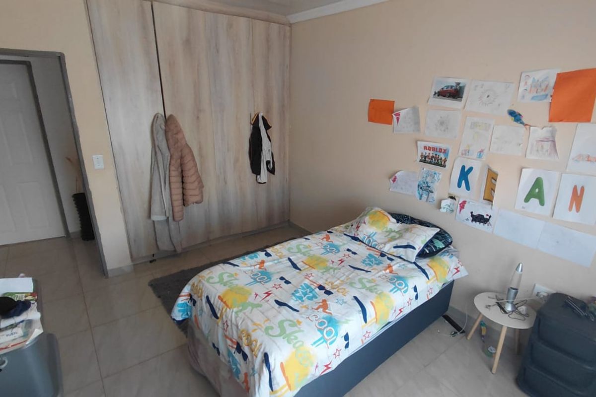 A functional bedroom featuring built-in cupboards and tiled flooring, providing a practical space with neutral wall finishes.