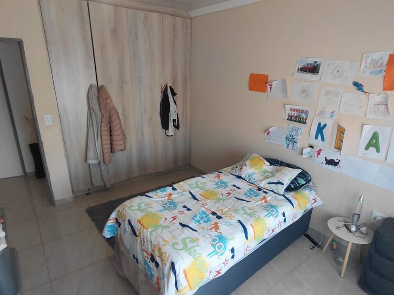 A functional bedroom featuring built-in cupboards and tiled flooring, providing a practical space with neutral wall finishes.