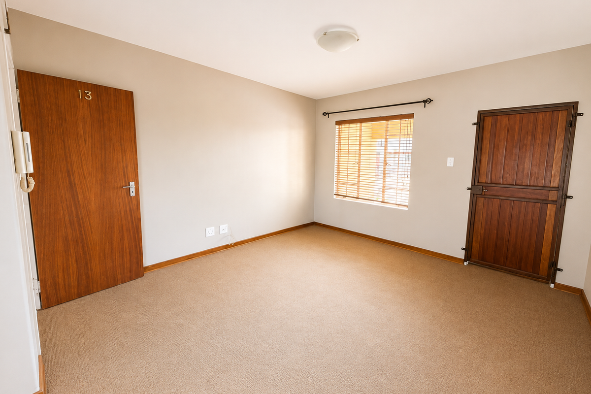 An empty bedroom featuring neutral walls, carpet flooring, a wooden entrance door, a stable-style door, and a window with fitted blinds.