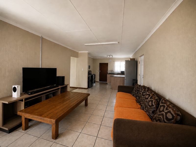 Open-plan living and kitchen area featuring tiled flooring and neutral wall tones, providing a functional layout for daily living.