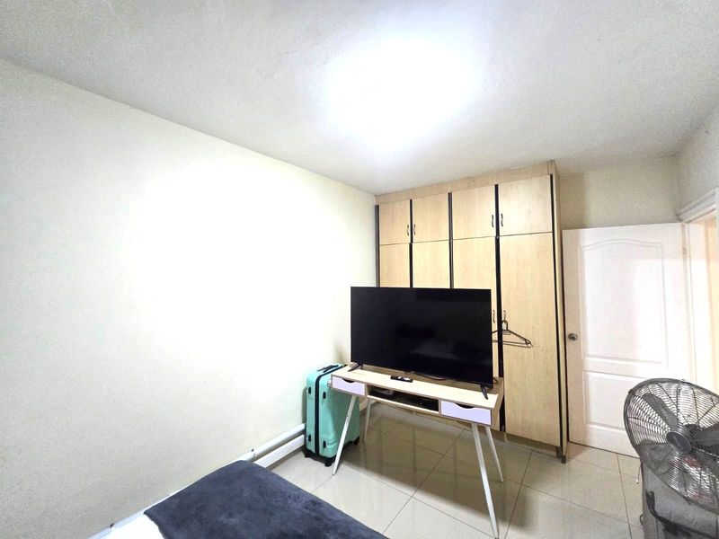 A bedroom featuring tiled flooring and a built-in wooden wardrobe, providing functional storage space.