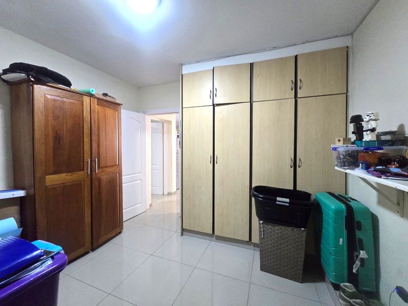 Bedroom featuring tiled flooring and extensive built-in cupboard storage with some visible wear to the cabinetry doors.