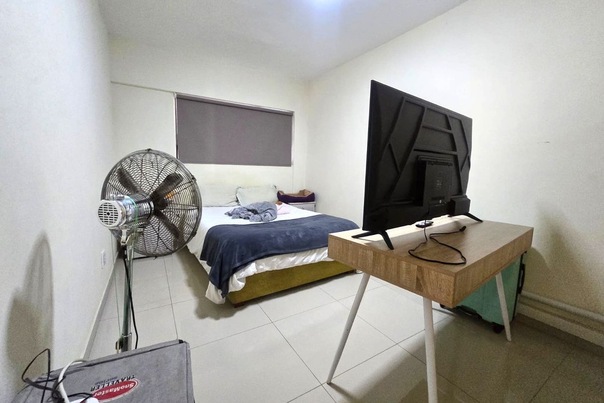 A functional bedroom featuring tiled flooring and a roller blind, providing a neutral base for personalization.