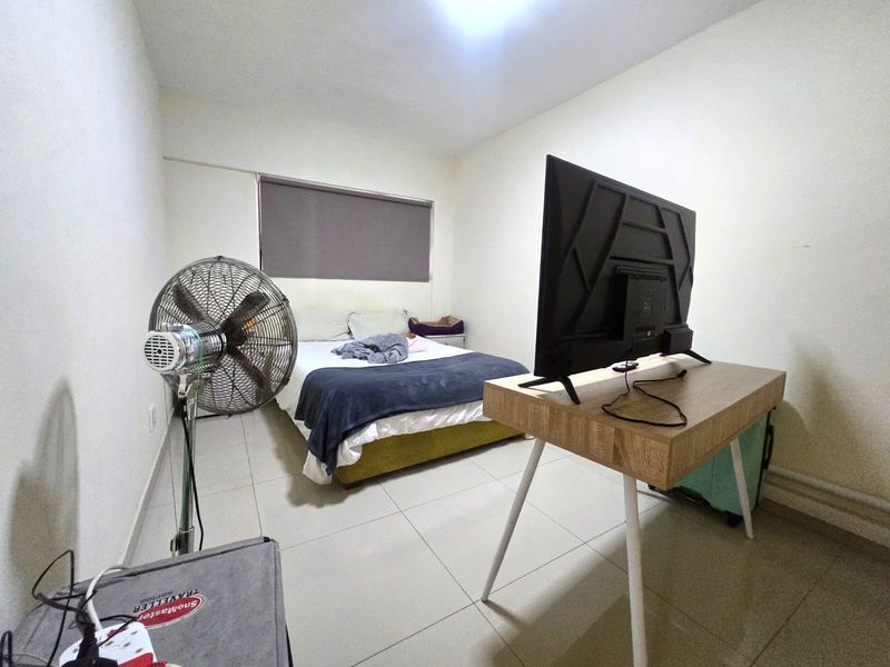 A functional bedroom featuring tiled flooring and a roller blind, providing a neutral base for personalization.