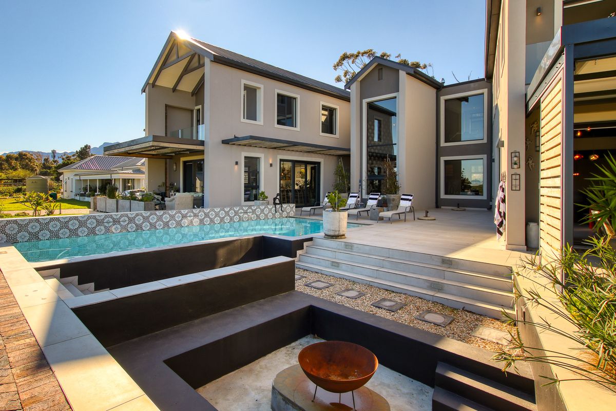 A modern rear exterior featuring a swimming pool, a sunken fire pit area, and a spacious tiled patio with contemporary architectural design.