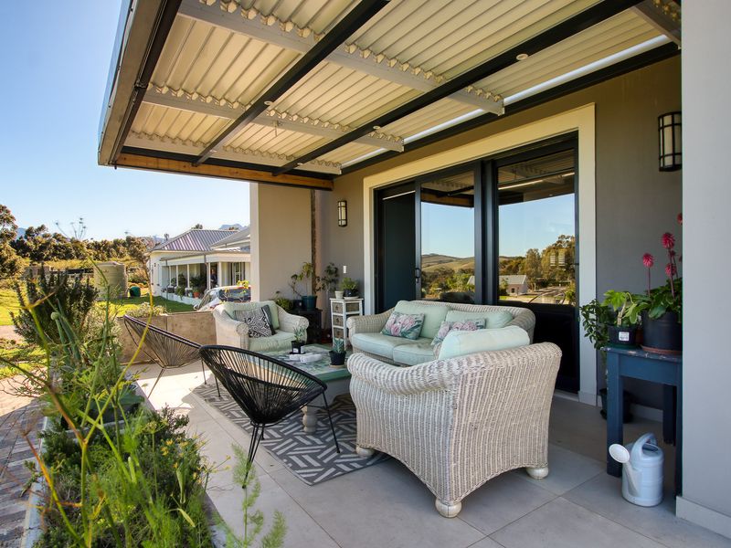 A covered outdoor patio area featuring tiled flooring, a corrugated metal roof, and sliding glass door access to the main living space.