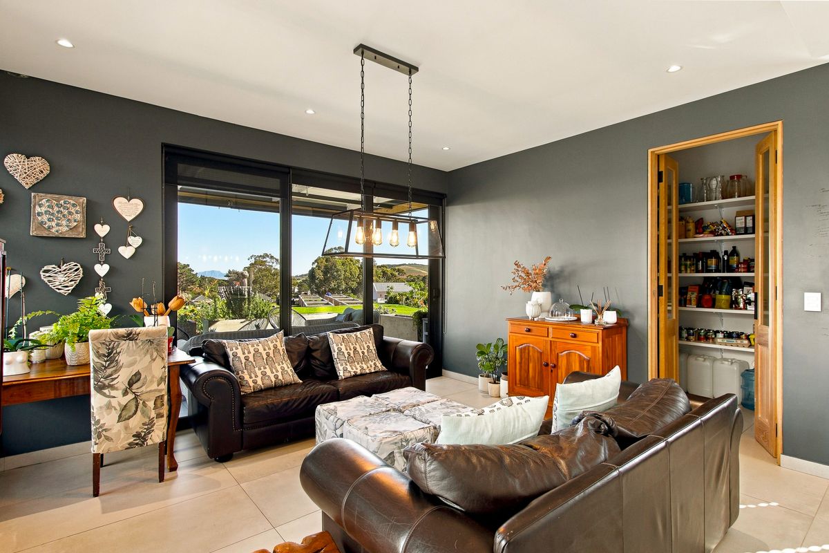 A modern living room featuring tiled floors, recessed lighting, a stylish pendant light, and large sliding doors leading to an outdoor area with a pantry.