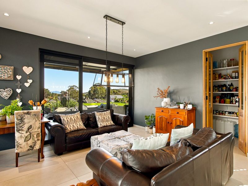 A modern living room featuring tiled floors, recessed lighting, a stylish pendant light, and large sliding doors leading to an outdoor area with a pantry.