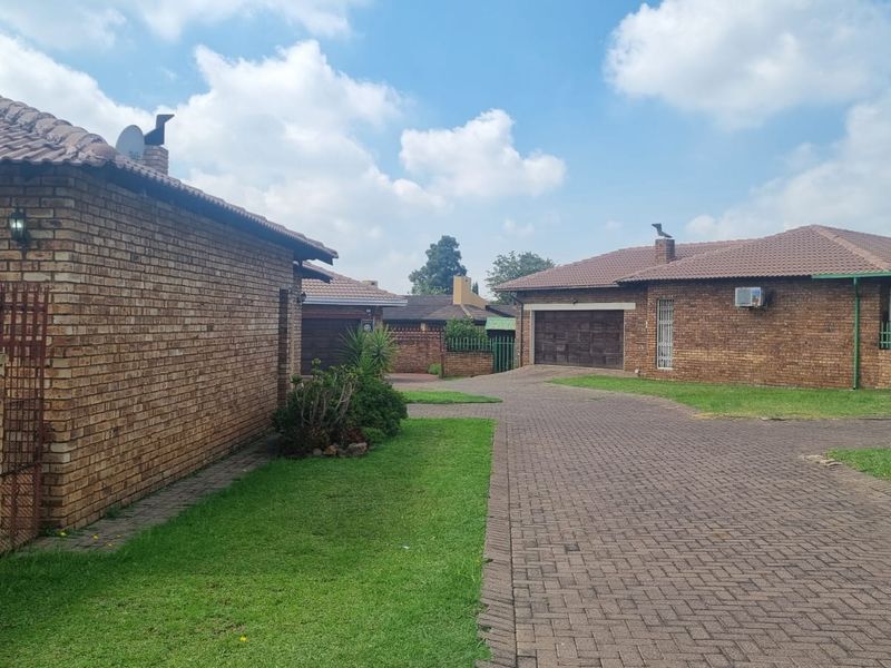 A view of the townhouse complex exterior featuring face brick construction, tiled roofing, and a paved driveway leading to the garage.