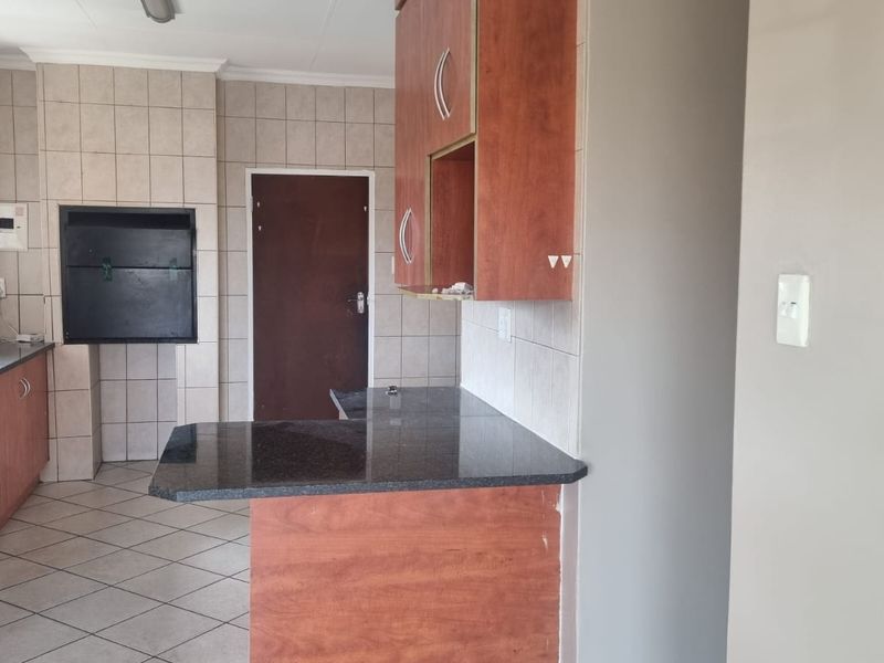 A functional kitchen featuring granite countertops, built-in cabinetry, an integrated oven, and a built-in indoor braai area with tiled finishes.