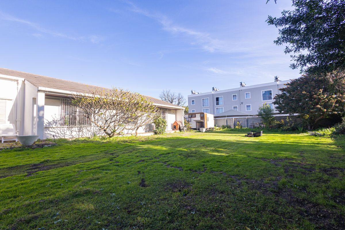 A spacious rear garden area featuring a lawn and boundary wall, providing a private outdoor space for the property.