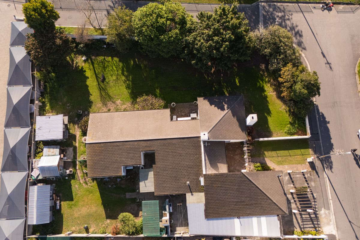 Aerial view of the property showing the roof structure, surrounding garden, driveway, and outdoor pergola area.