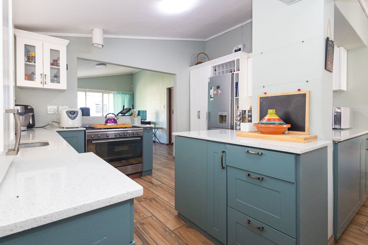 Modern kitchen featuring blue cabinetry, white quartz countertops, a gas stove, and wood-look tiled flooring with an open-plan layout.