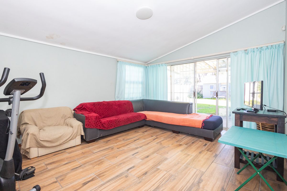 Living room featuring tiled flooring, vaulted ceilings, and sliding glass doors providing access to the rear garden area.