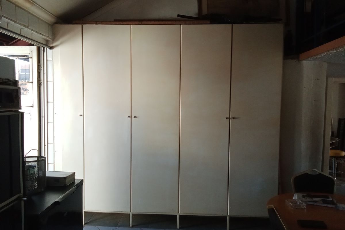 A bedroom area featuring a large wall of built-in cupboards with a dated finish, requiring cosmetic updates to improve the overall aesthetic.