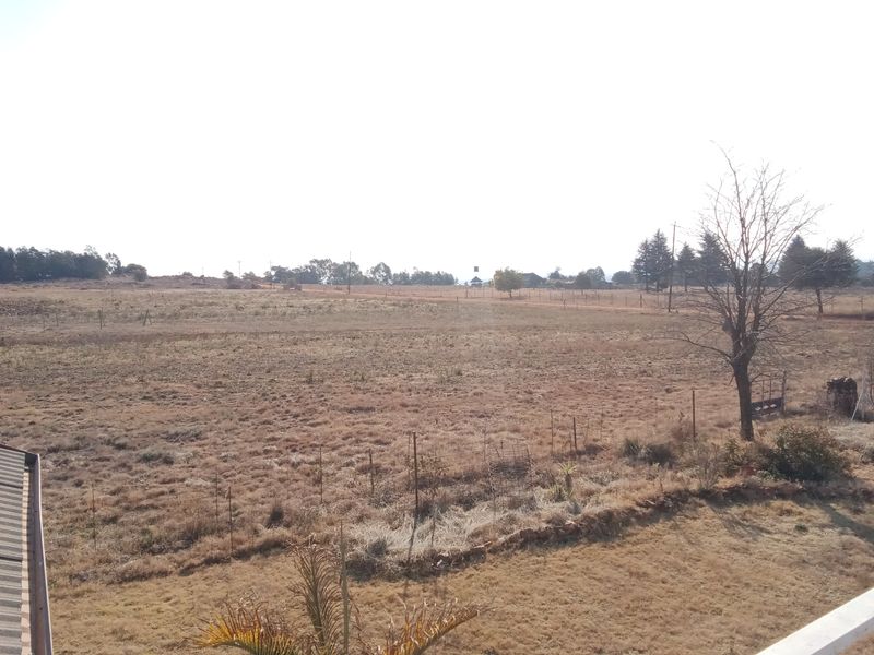 Expansive view of the open farm landscape featuring dry grazing fields and perimeter wire fencing.