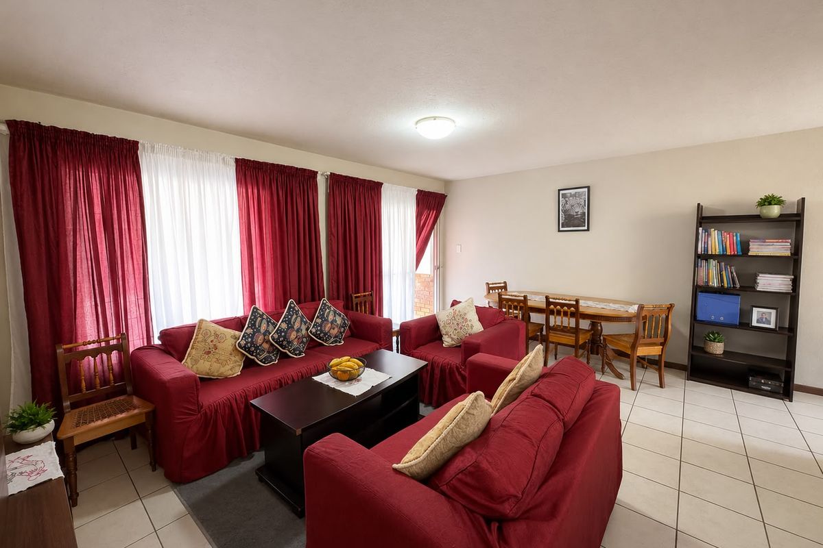 Spacious open-plan living and dining area featuring neutral wall tones and tiled flooring, with direct access to an outdoor space via sliding doors.