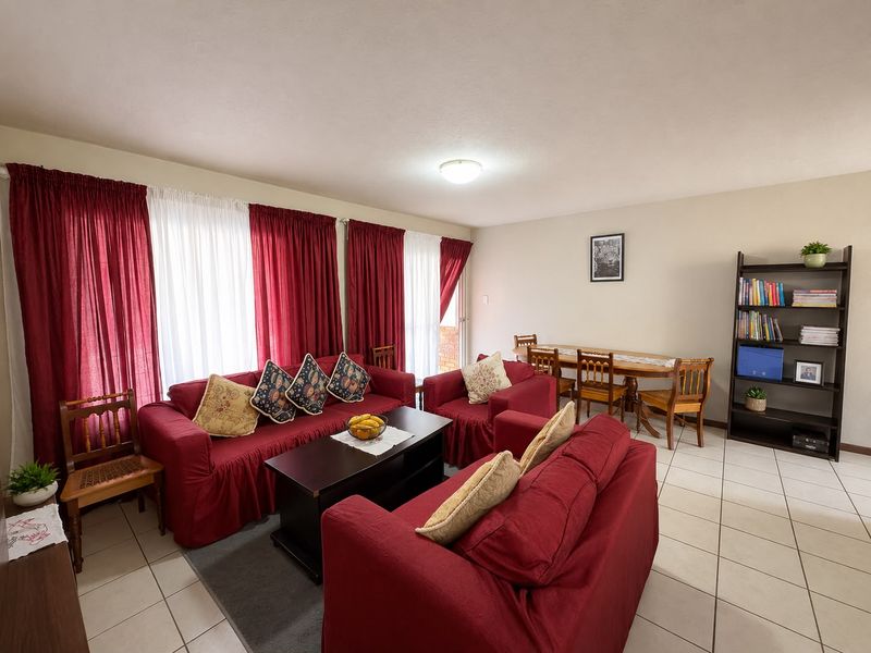 Spacious open-plan living and dining area featuring neutral wall tones and tiled flooring, with direct access to an outdoor space via sliding doors.