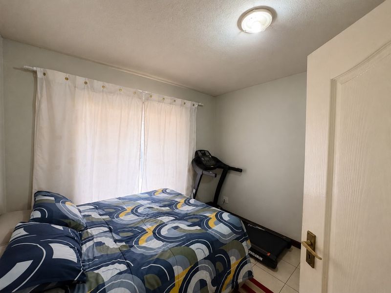 A standard bedroom featuring tiled flooring and a central ceiling light fixture, providing a functional space for rest.