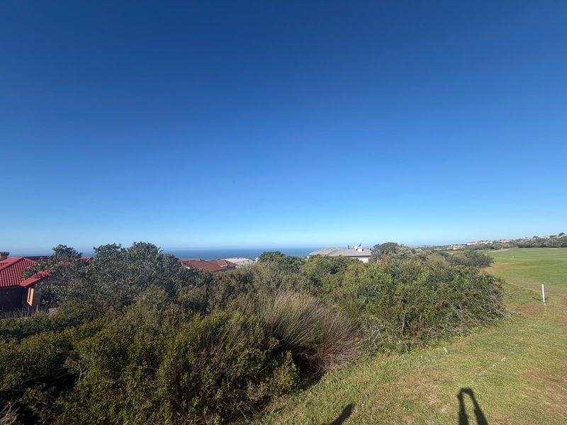 A scenic view overlooking a coastal landscape and adjacent golf course, showcasing the natural surroundings of the residential land.