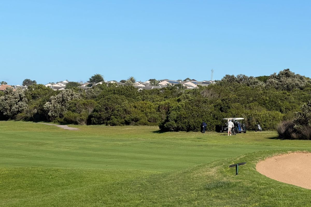 A scenic view overlooking a well-maintained golf course fairway with a sand bunker and surrounding natural vegetation.