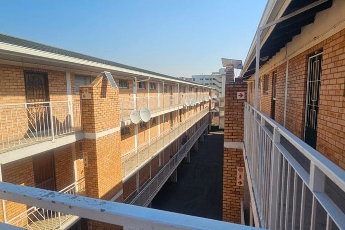 Exterior view of an apartment complex featuring brick facades, external walkways, and metal safety railings.